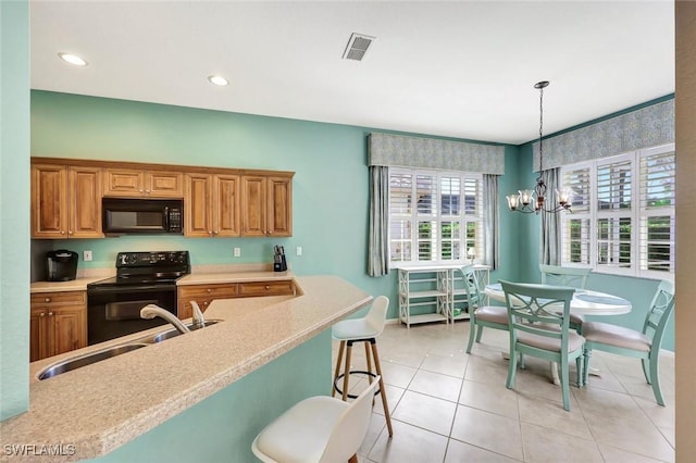 kitchen with visible vents, a sink, light countertops, black appliances, and a notable chandelier