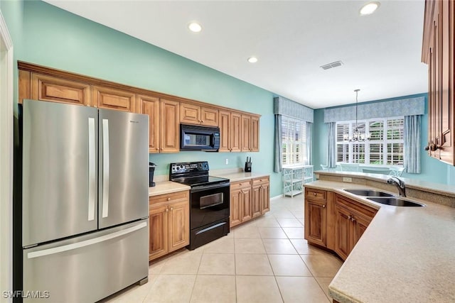 kitchen with decorative light fixtures, light tile patterned floors, light countertops, visible vents, and black appliances