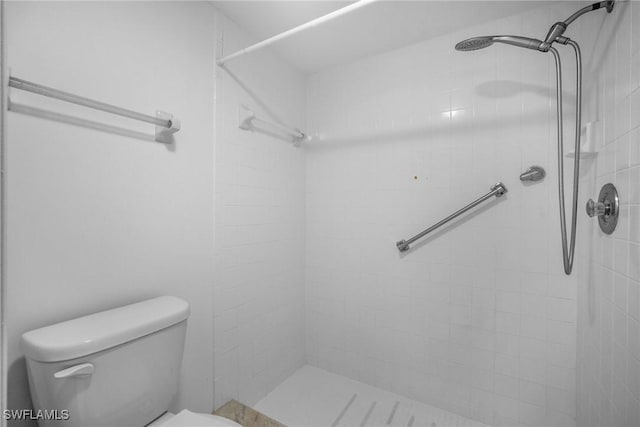 bathroom with a tile shower and toilet