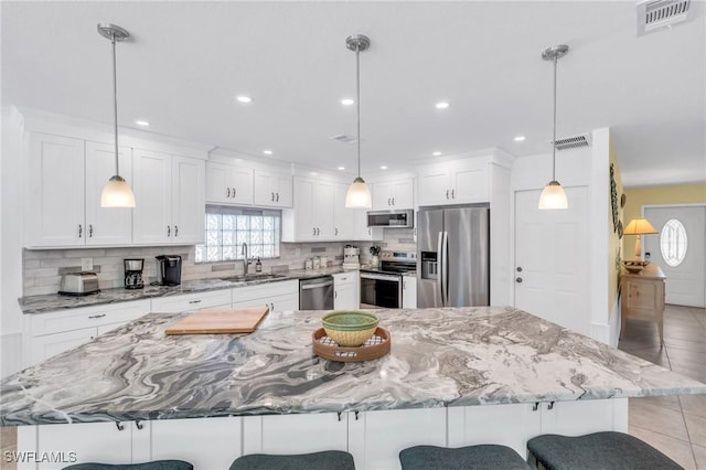 kitchen with appliances with stainless steel finishes, sink, decorative light fixtures, a large island, and white cabinets