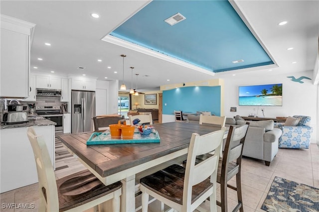 tiled dining room featuring a tray ceiling