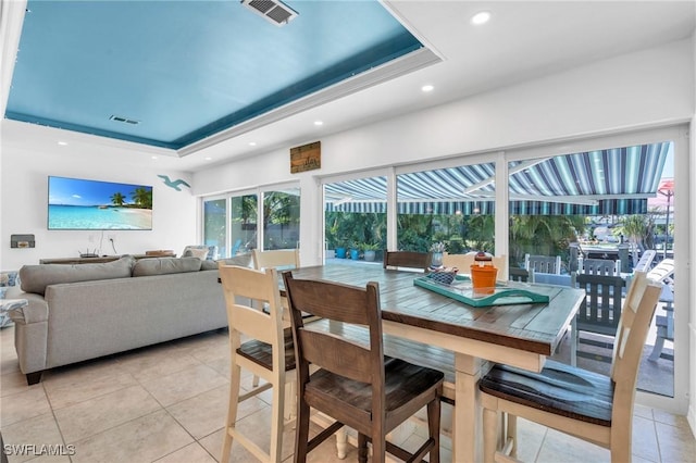 tiled dining space featuring a raised ceiling