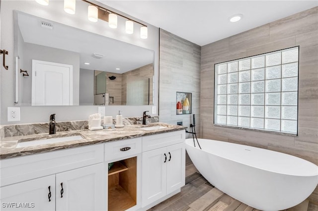 bathroom with hardwood / wood-style floors, separate shower and tub, tile walls, and vanity