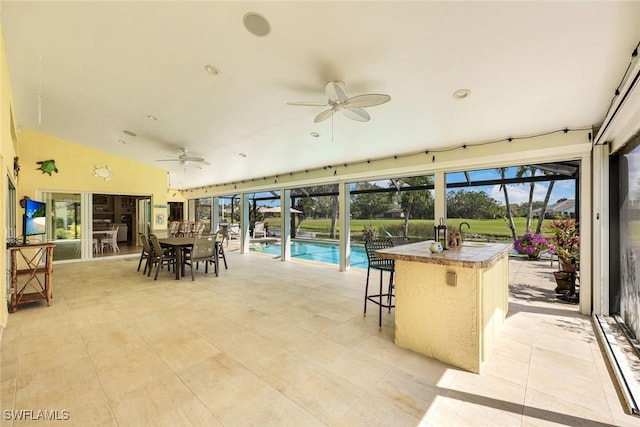 view of patio / terrace featuring ceiling fan, glass enclosure, a pool, outdoor dry bar, and outdoor dining space