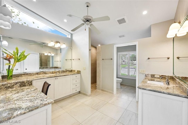 bathroom featuring a tile shower, two vanities, a sink, and visible vents