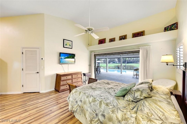 bedroom featuring baseboards, a ceiling fan, wood finished floors, access to exterior, and high vaulted ceiling