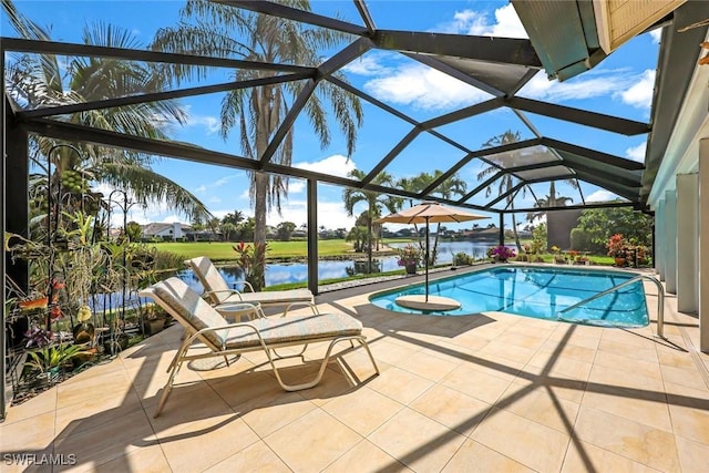 outdoor pool with glass enclosure, a water view, and a patio