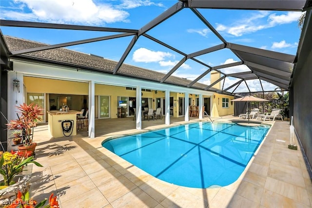 pool with a lanai, outdoor dry bar, and a patio