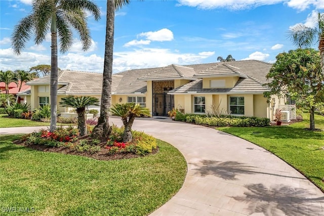 view of front of property featuring ac unit, a front lawn, concrete driveway, and stucco siding