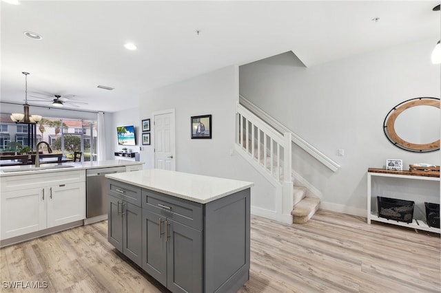 kitchen with gray cabinetry, stainless steel dishwasher, light hardwood / wood-style floors, pendant lighting, and sink