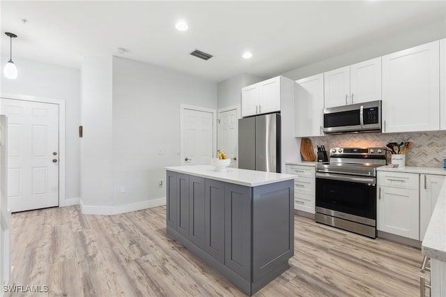 kitchen with white cabinetry, pendant lighting, a kitchen island, stainless steel appliances, and decorative backsplash