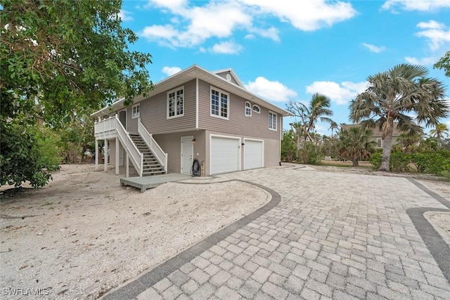 back of property with driveway, an attached garage, and stairs