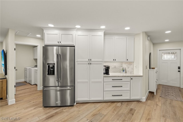 kitchen with light wood-type flooring, white cabinetry, high quality fridge, and washer and clothes dryer