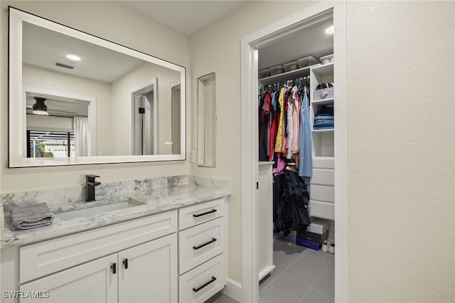 bathroom with tile patterned flooring, vanity, visible vents, and a walk in closet