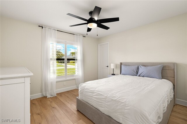 bedroom featuring a ceiling fan, baseboards, and light wood finished floors