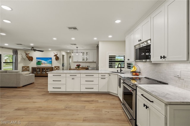 kitchen featuring visible vents, appliances with stainless steel finishes, open floor plan, a sink, and a peninsula