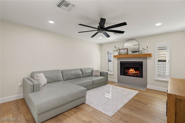 living room with light wood-type flooring, a fireplace with flush hearth, visible vents, and recessed lighting