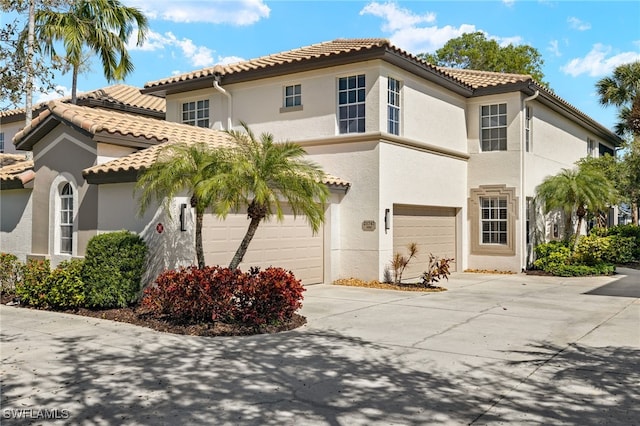 mediterranean / spanish home with concrete driveway, a tiled roof, and stucco siding