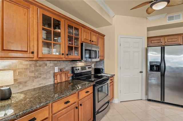 kitchen with brown cabinets, visible vents, appliances with stainless steel finishes, glass insert cabinets, and dark stone countertops