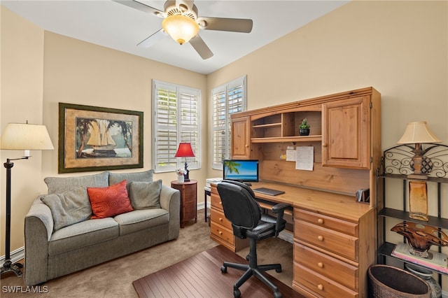 carpeted office with ceiling fan and baseboards