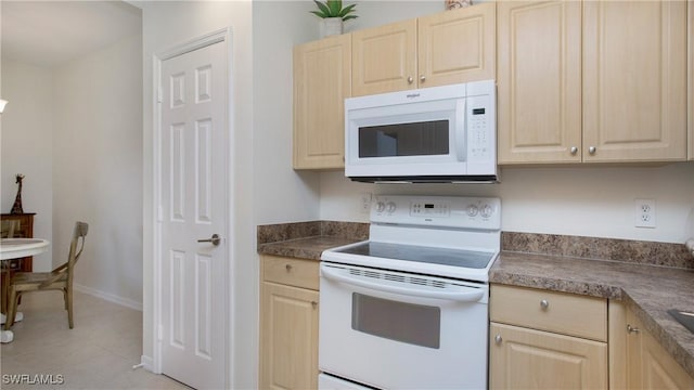 kitchen with white appliances, light tile patterned floors, baseboards, dark countertops, and light brown cabinetry