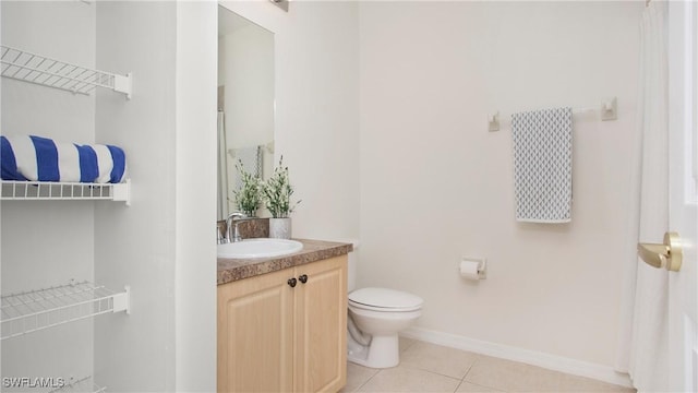 bathroom with toilet, tile patterned flooring, vanity, and baseboards