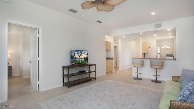 living room featuring light tile patterned floors, visible vents, and ceiling fan with notable chandelier