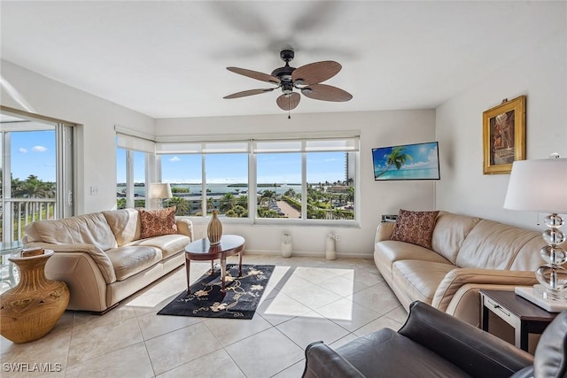 living room featuring baseboards, a healthy amount of sunlight, a ceiling fan, and light tile patterned floors