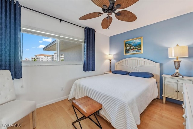 bedroom with baseboards, a ceiling fan, and light wood-style floors