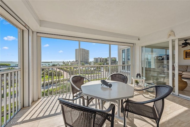 sunroom with ceiling fan and a city view