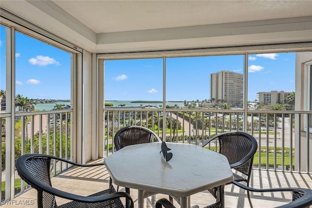 sunroom / solarium featuring a city view, a wealth of natural light, and a water view