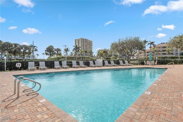 community pool with fence and a patio area