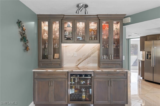 bar with beverage cooler, a bar, tasteful backsplash, and stainless steel fridge