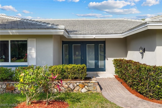 view of exterior entry with a tiled roof and stucco siding