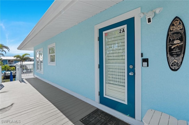 view of exterior entry with covered porch and stucco siding