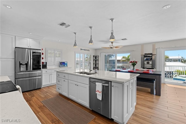 kitchen with a sink, stainless steel appliances, light countertops, and white cabinets