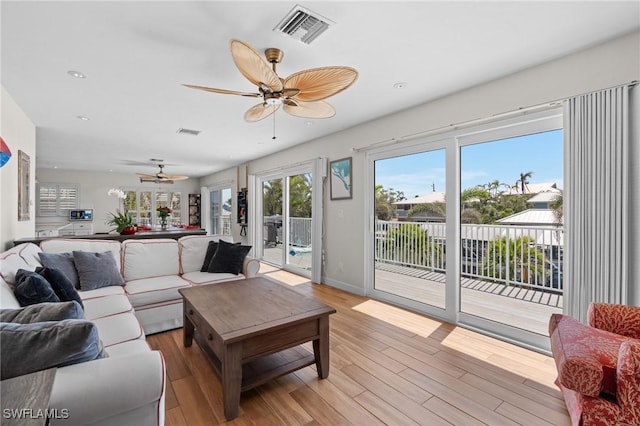 living area featuring light wood-type flooring, ceiling fan, and visible vents