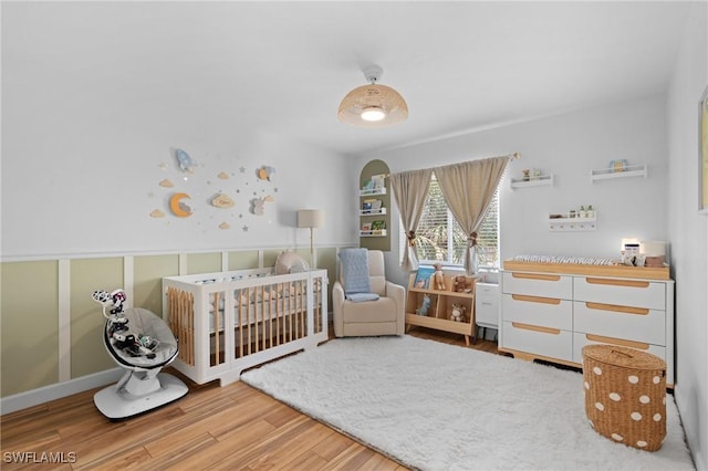 bedroom featuring a nursery area and light wood-style floors