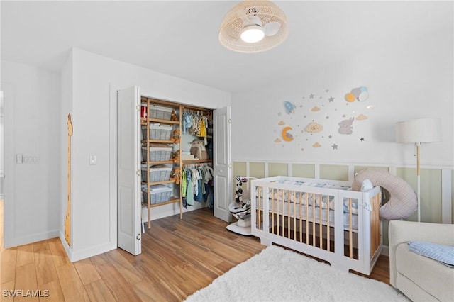 bedroom featuring a closet, wainscoting, and wood finished floors