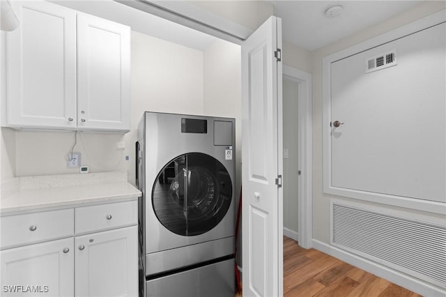 washroom featuring washer / dryer, visible vents, cabinet space, and light wood-style flooring