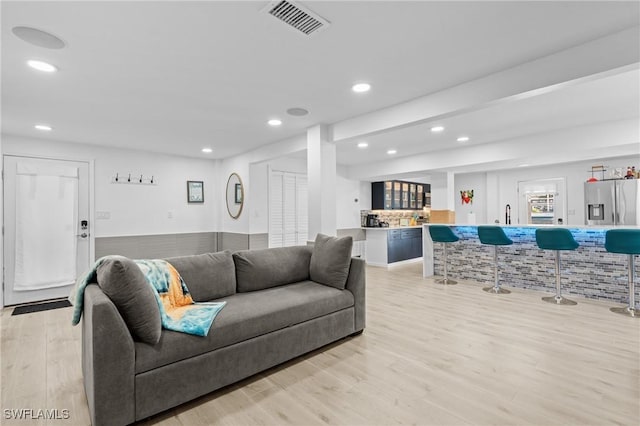 living room featuring light wood-type flooring, visible vents, indoor wet bar, and recessed lighting