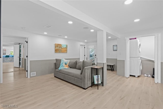 living area with light wood-style flooring, recessed lighting, visible vents, and stacked washer / drying machine