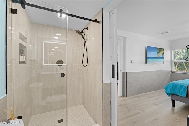 ensuite bathroom with tile walls, visible vents, ensuite bathroom, a shower stall, and wood finished floors