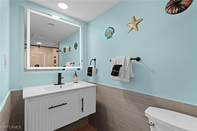 bathroom featuring a wainscoted wall, tile walls, visible vents, toilet, and vanity