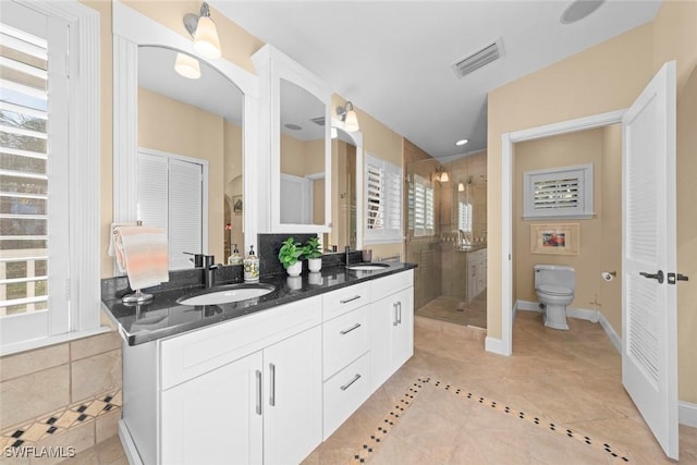 bathroom featuring double vanity, visible vents, a sink, a shower stall, and baseboards