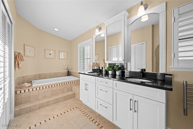 bathroom with tile patterned floors, double vanity, a sink, and a bath