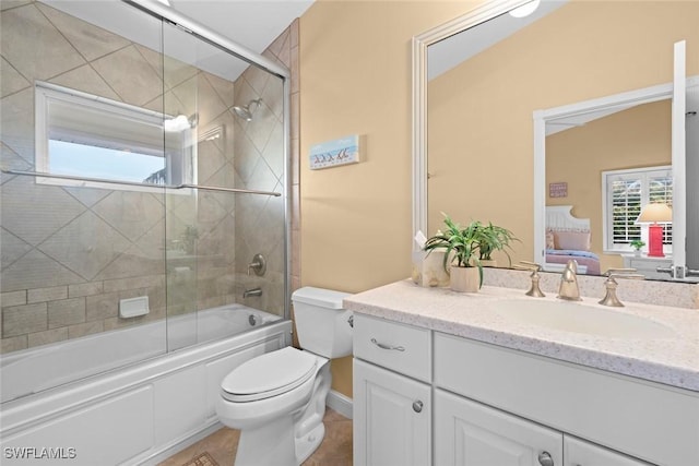 ensuite bathroom with enclosed tub / shower combo, connected bathroom, vanity, and toilet