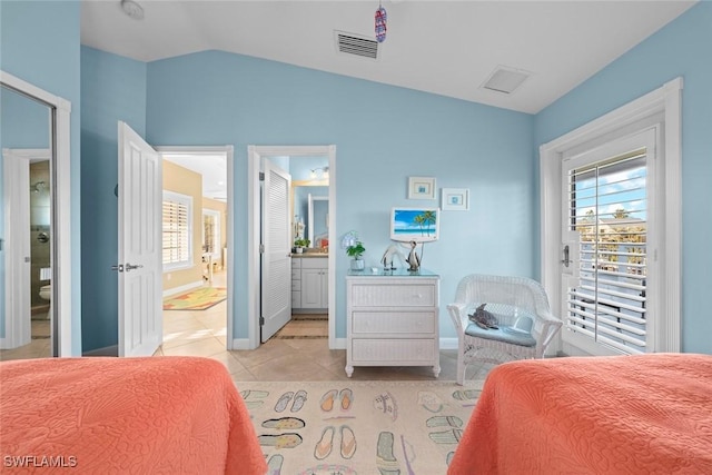 bedroom featuring light tile patterned flooring, connected bathroom, visible vents, baseboards, and vaulted ceiling