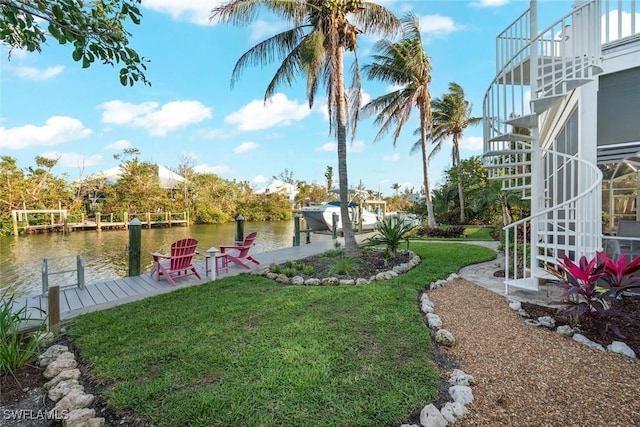 view of yard featuring a dock, a water view, boat lift, and stairs