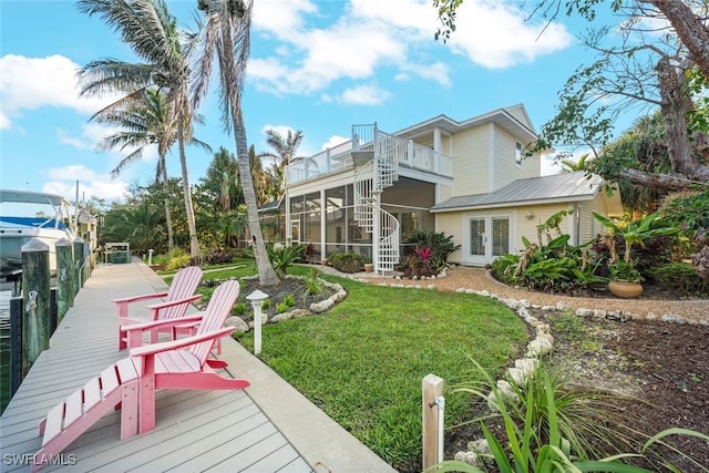 back of house with a balcony, a sunroom, stairway, and a yard